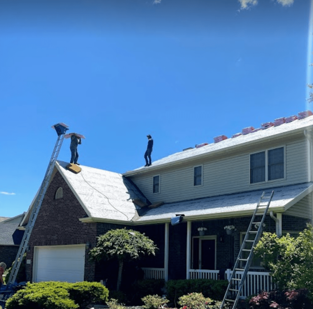 Roofers installing shingles on second story house